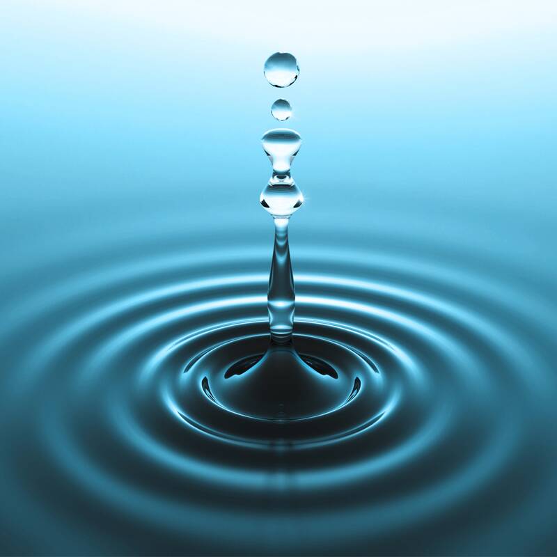Ein einzelner Wassertropfen fällt in ruhiges Wasser und erzeugt konzentrische Wellenmuster.